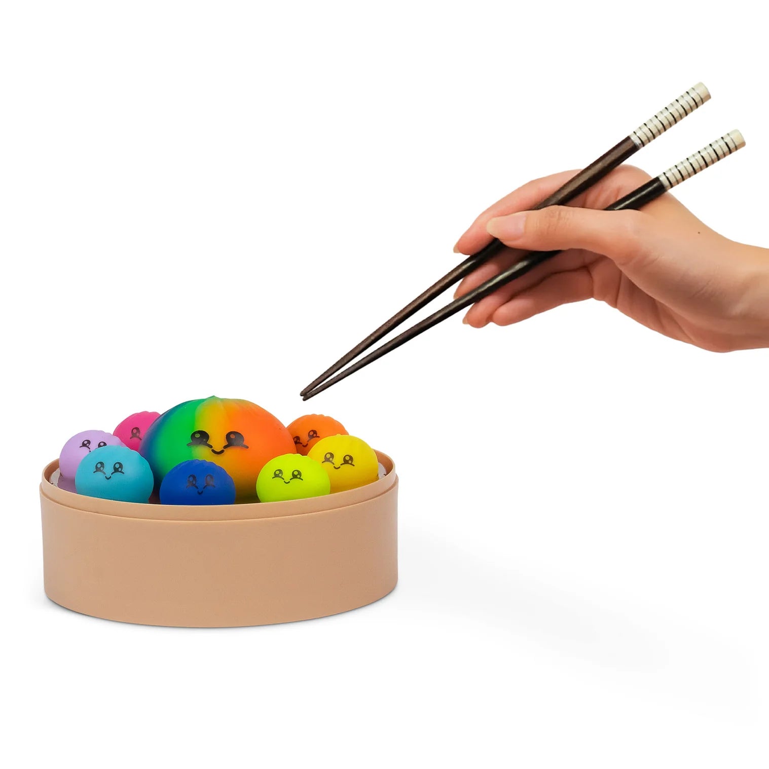 Colorful toy food items in a container with a hand holding chopsticks on a white background